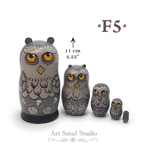 May include: A set of five nesting dolls painted as grey owls with yellow eyes and black beaks. The largest doll is 11 cm or 4.33 inches tall. The owls feature detailed feather patterns and a dark grey base. The text F5 and Art Smal Studio are visible.