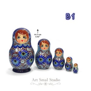 Ensemble de 5 poupées gigognes russes en bois peint à la main, finition nacrée bleue avec motifs floraux traditionnels. Présentation du format de la plus grande matriochka (12,5 cm). Modèle B1.