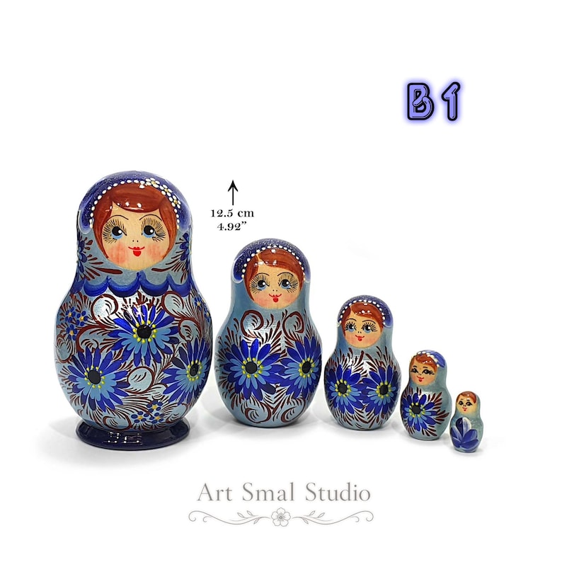 Ensemble de 5 poupées gigognes russes en bois peint à la main, finition nacrée bleue avec motifs floraux traditionnels. Présentation du format de la plus grande matriochka (12,5 cm). Modèle B1.