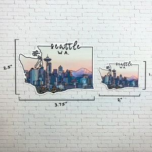May include: Two Seattle, WA skyline stickers. The larger sticker is 3.75 inches wide by 2.5 inches tall. The smaller sticker is 2 inches wide by 1.5 inches tall. Both stickers feature a stylized outline of the state of Washington with the Seattle skyline and the Space Needle.