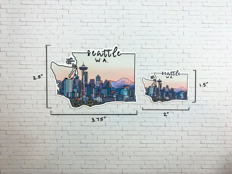 May include: Two Seattle, WA skyline stickers. The larger sticker is 3.75 inches wide by 2.5 inches tall. The smaller sticker is 2 inches wide by 1.5 inches tall. Both stickers feature a stylized outline of the state of Washington with the Seattle skyline and the Space Needle.