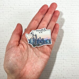 May include: A sticker depicting the Seattle skyline with the Space Needle, mountains, and the text "Seattle WA."