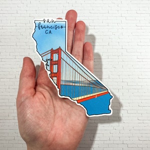 Op de afbeelding: Een sticker in de vorm van de staat Californi&euml; met de Golden Gate Bridge en de tekst "san francisco CA." erop gedrukt.