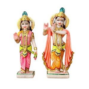 May include: Hand-painted marble statue of Radha Krishna, a Hindu deity couple, with intricate details and vibrant colours. The statue features Radha holding a lotus flower and Krishna playing the flute.