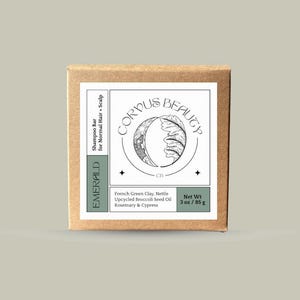 May include: A brown cardboard box with a white label featuring the text "CORPUS BEAUTY" and "EMERALD." The label also includes the text "Shampoo Bar for Normal Hair + Scalp" and product details. Net weight is 3 oz / 85 g.