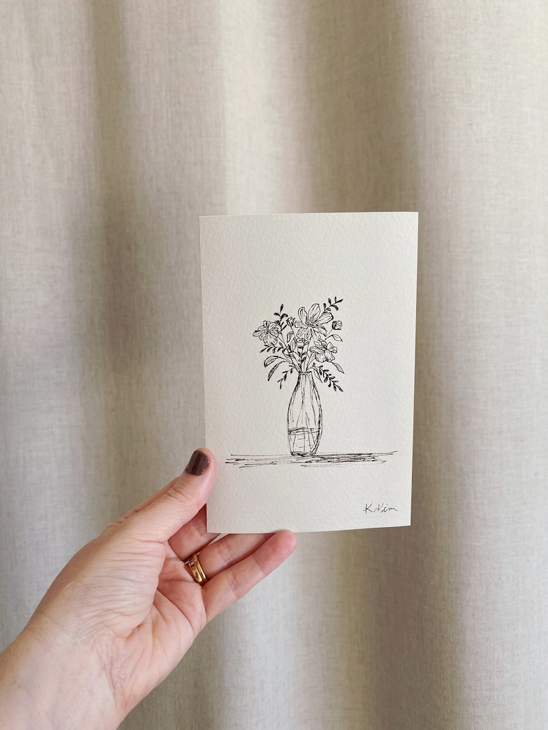 May include: A black and white line drawing of a bouquet of flowers in a vase. The drawing is signed "K.Hem".