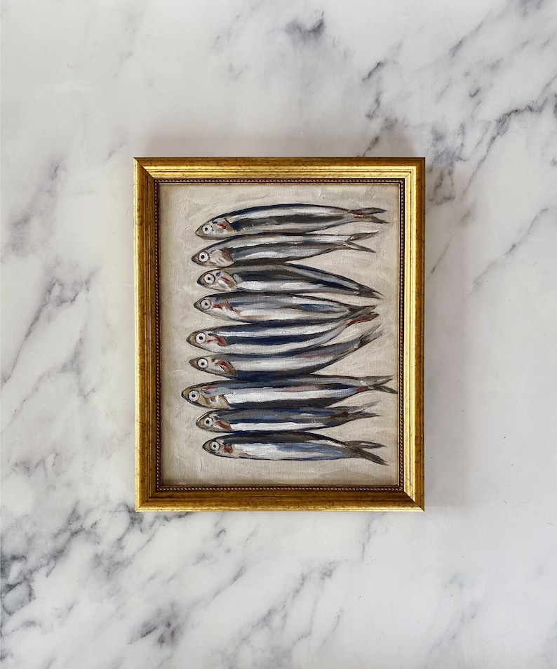 May include: A framed painting of a row of silver fish on a white background. The frame is gold and has a decorative border.
