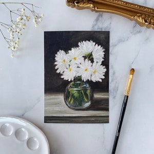 May include: A painting of a bouquet of white daisies in a clear glass vase on a dark background.