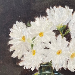 May include: A close-up of a painting of white daisies in a green vase against a dark background.
