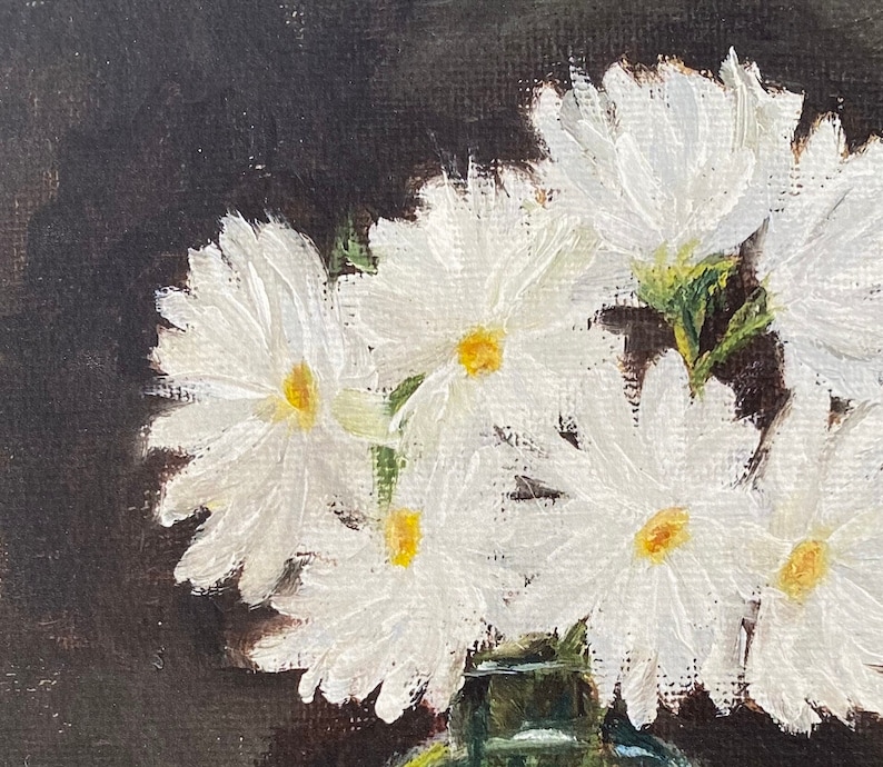 May include: A close-up of a painting of white daisies in a green vase against a dark background.