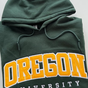 May include: A dark green hooded sweatshirt with the words "OREGON UNIVERSITY" in white and yellow lettering.