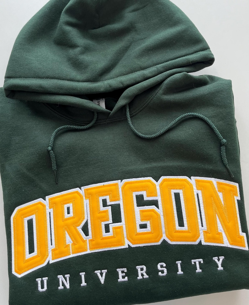May include: A dark green hooded sweatshirt with the words "OREGON UNIVERSITY" in white and yellow lettering.