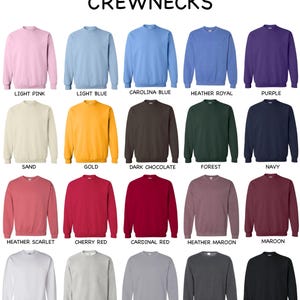 Może przedstawiać: Kolekcja dwudziestu bluz z okrągłym dekoltem wyświetlanych w siatce, oznaczonych nazwami kolor&oacute;w, w tym light pink, light blue, carolina blue, heather royal, purple, sand, gold, dark chocolate, forest, navy, heather scarlet, cherry red, cardinal red, heather maroon, maroon, white, ash, sport grey, dark heather oraz black.