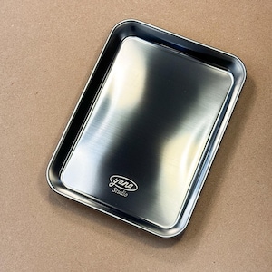 May include: A silver metal tray with a brushed finish. The tray has a slightly raised edge and a logo that reads "yana Studio".