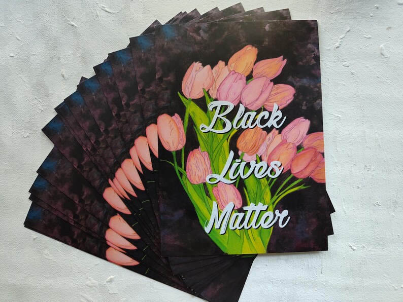 May include: A collection of art prints displaying a watercolour illustration of pink and orange tulips with green stems and leaves. The words "Black Lives Matter" are written in white script.