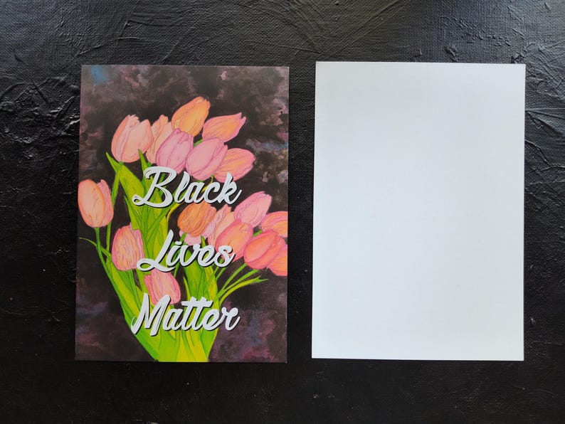 May include: A greeting card featuring a bouquet of pink and orange tulips with green leaves, and the text "Black Lives Matter." The background is dark and textured. A blank white card is next to it.