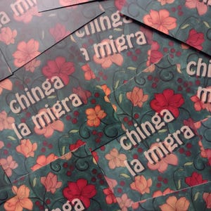 Puede incluir: Una pila de pegatinas coloridas con un patr&oacute;n floral y el texto "chinga la migra" repetido en cada pegatina.
