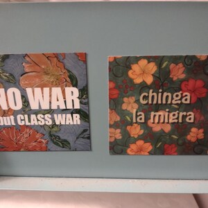 Puede incluir: Dos imanes cuadrados con patrones florales y texto blanco en negrita. El im&aacute;n de la izquierda dice "NO WAR but CLASS WAR". El im&aacute;n de la derecha dice "chinga la migra".