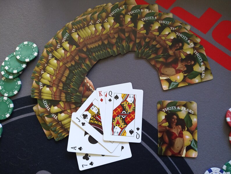 May include: A deck of playing cards with a design of pears and women on the back of the cards. The cards are fanned out in a semi-circle.  The cards are arranged in a semi-circle with the face cards of a standard deck of cards in the center. The face cards are the Jack, Queen, King, and Ace of Spades.
