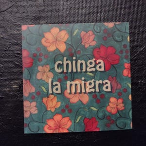 Puede incluir: Un fondo azul verdoso con un patr&oacute;n floral en tonos de rojo, naranja y amarillo. El texto "chinga la migra" est&aacute; escrito en letras blancas.