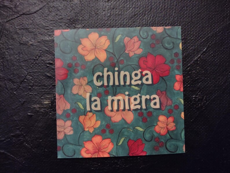 Puede incluir: Un fondo azul verdoso con un patr&oacute;n floral en tonos de rojo, naranja y amarillo. El texto "chinga la migra" est&aacute; escrito en letras blancas.