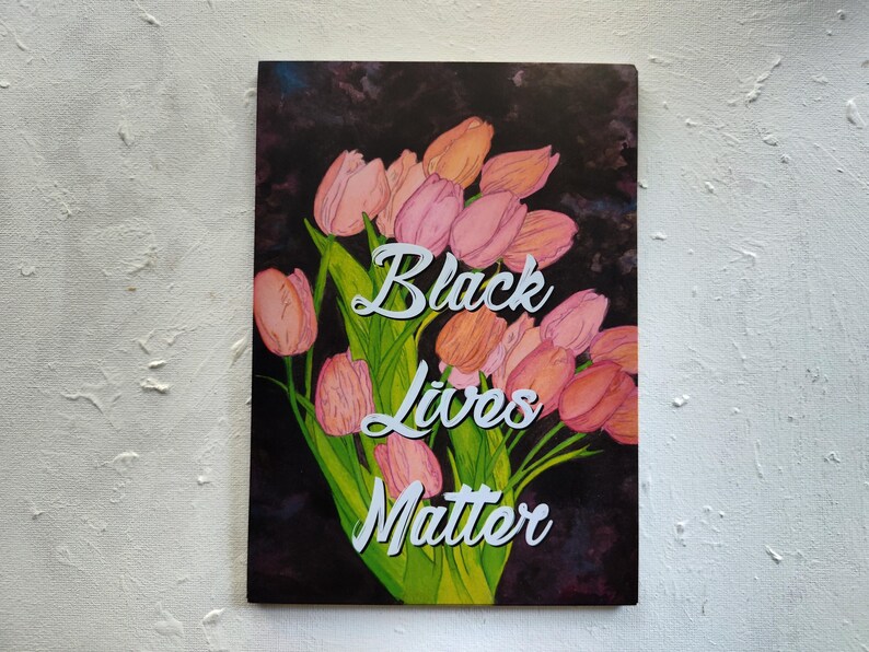 May include: An art print showing a bouquet of pink and orange tulips with green stems and leaves against a dark background. The words "Black Lives Matter" are written in white script across the image.