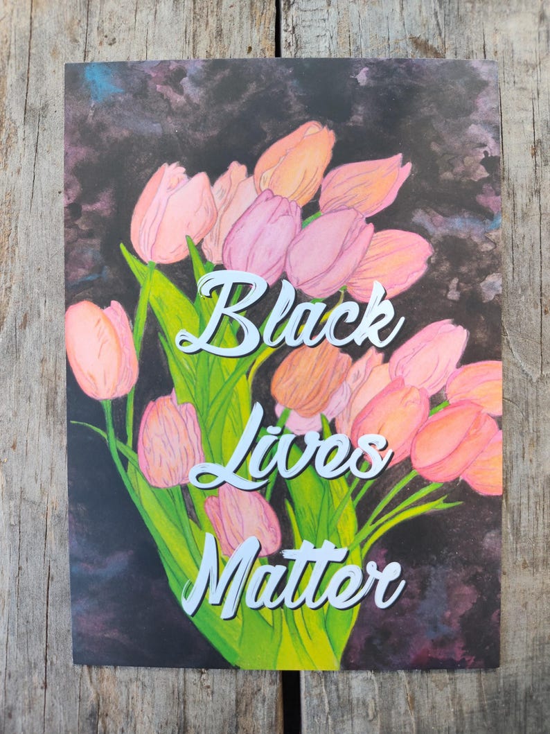 May include: An art print showing a bouquet of pink and peach tulips with green leaves against a dark backdrop. The words "Black Lives Matter" are written in white script across the image.