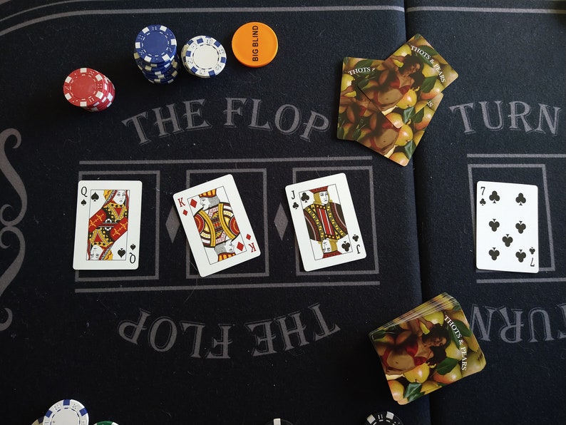 May include: A poker table with a green felt surface, blue and red poker chips, and playing cards. The cards are arranged in a row, with the text "The Flop" above them. The text "Turn" is on the right side of the table.