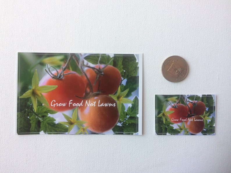 May include: Two stickers with a green leafy background and red tomatoes. The text on the stickers reads "Grow Food Not Lawns".