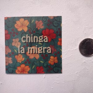 Puede incluir: Una pegatina con un dise&ntilde;o floral en tonos rojos, naranjas y verdes. La pegatina tiene el texto "chinga la migra" en letras blancas.