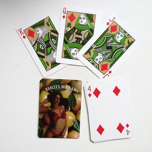 May include: A set of playing cards featuring a queen, jack, king, and four of diamonds. The cards have a green and gold design with a person's face on each card. The four of diamonds card has a red background with four red diamonds.