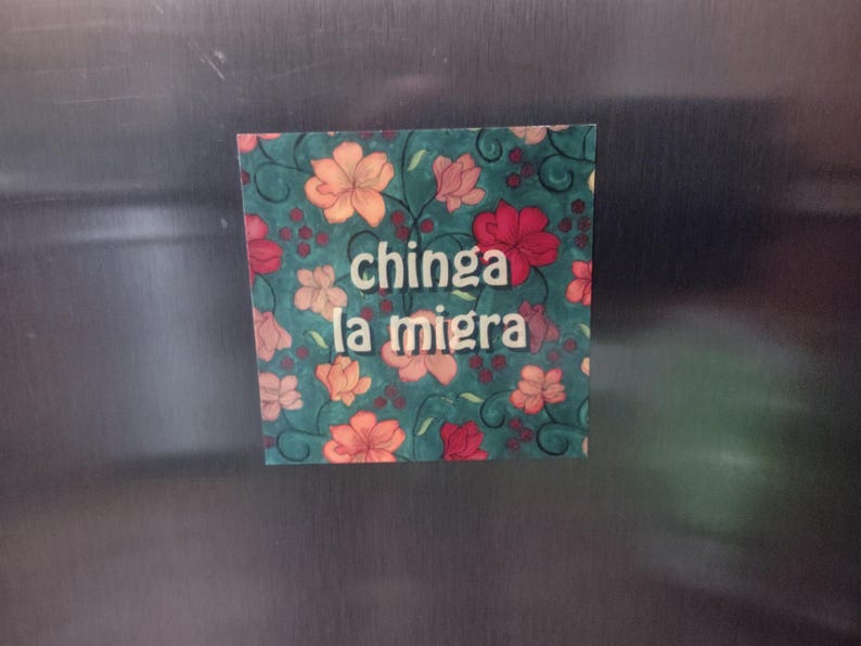 Puede incluir: Un im&aacute;n con un dise&ntilde;o floral y el texto "chinga la migra" en letras blancas.