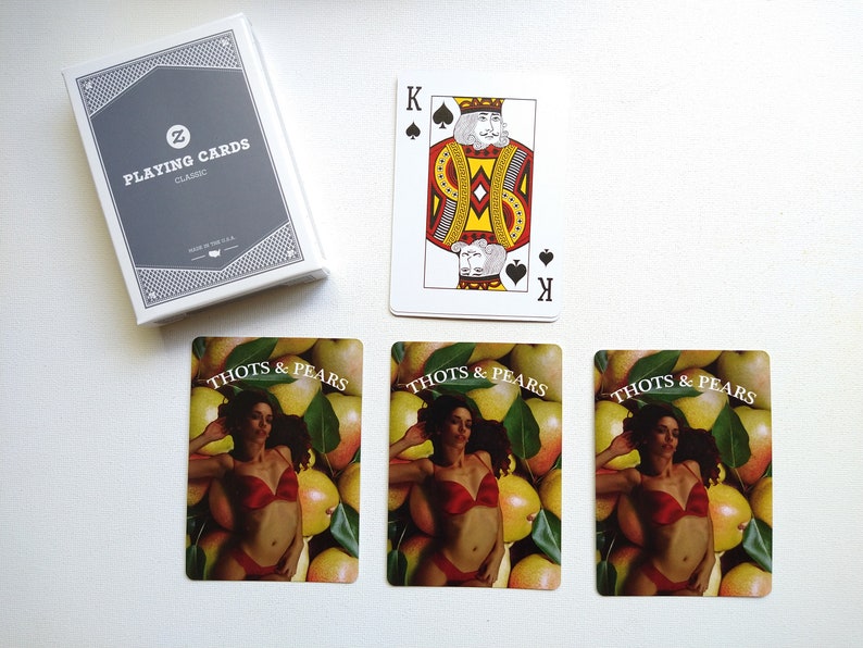 May include: Three playing cards with a woman in a red bikini lying on a bed of pears. The cards are labeled "Thots & Pears".