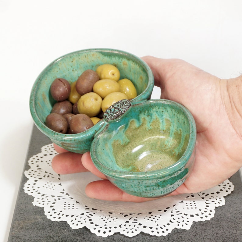May include: A green and brown ceramic serving dish with two bowls. The dish is filled with green and brown olives.