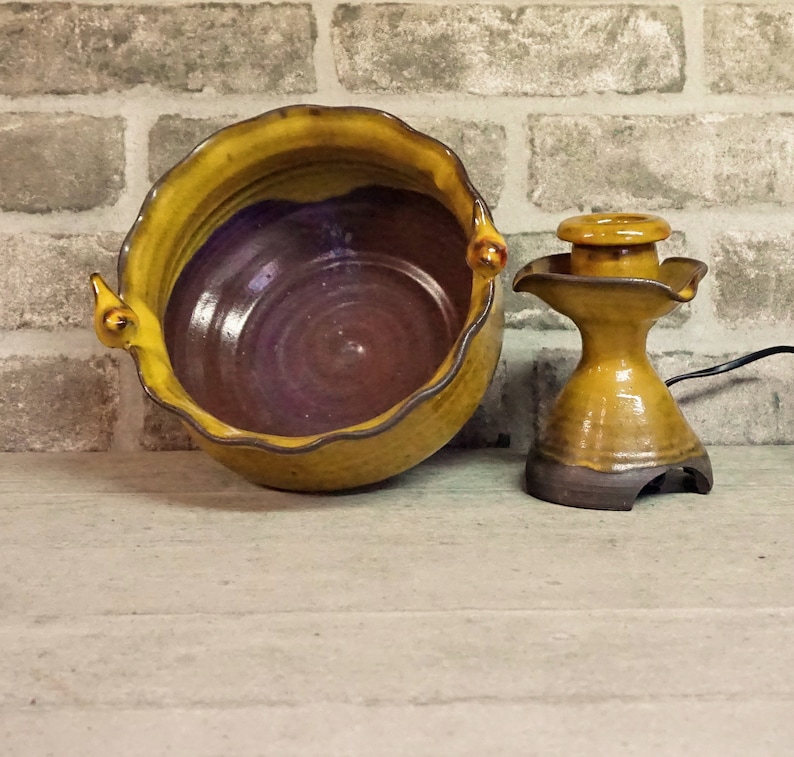 May include: A yellow and brown ceramic bowl with a wavy rim and a brown ceramic water fountain with a yellow glaze.