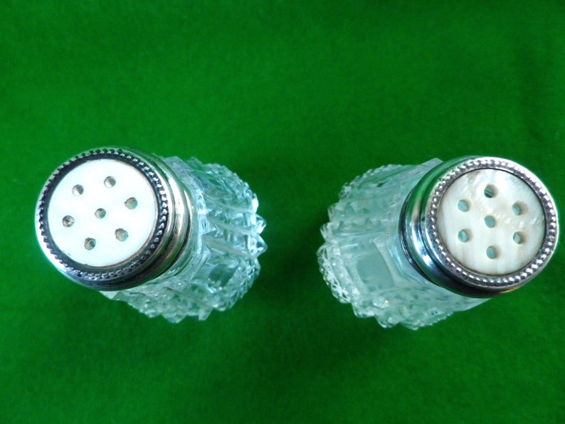 2 mother of pearl and silver top salt and pepper pots with glass bases