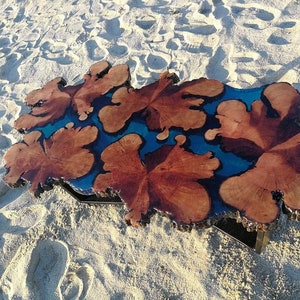 May include: A unique coffee table made from a large piece of wood with a blue resin inlay. The wood has a natural, rustic look and the resin adds a modern touch. The table is perfect for a living room or dining room.