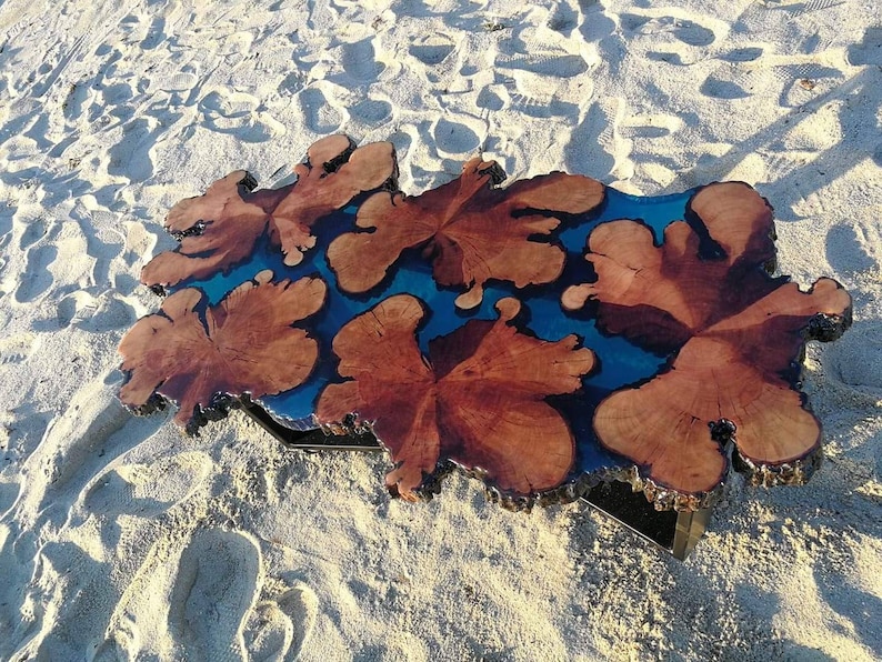 May include: A unique coffee table made from a large piece of wood with a blue resin inlay. The wood has a natural, rustic look and the resin adds a modern touch. The table is perfect for a living room or dining room.