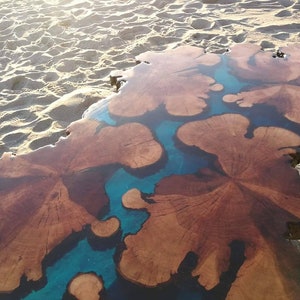 May include: A large wooden slab with a natural wood grain pattern, filled with blue epoxy resin. The resin creates a unique, flowing design.