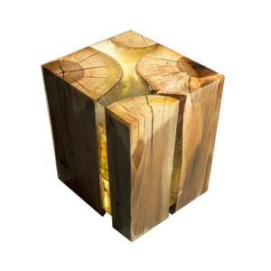 Könnte beinhalten: Ein Hocker aus Holz mit einer transparenten Harzeinlage. Das Harz ist mit Holzmaserung gefüllt und hat einen warmen, gelben Schimmer. Der Hocker ist aus Naturholz gefertigt und hat ein rustikales, handgemachtes Aussehen.