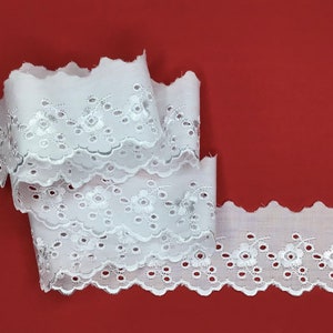 May include: White cotton lace trim with a scalloped edge and embroidered floral design.