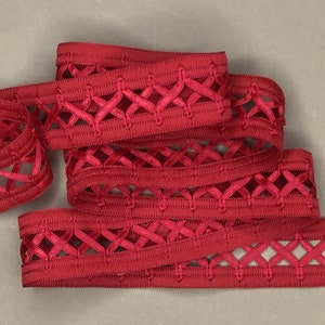 May include: Red satin ribbon with a woven diamond pattern. The ribbon has a delicate, openwork design.