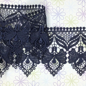 May include: Navy blue lace trim featuring a delicate floral design. The trim has a scalloped edge and is ideal for adding a touch of elegance to any project.