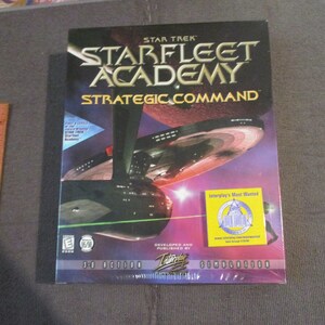 May include: A sealed Star Trek: Starfleet Academy Strategic Command PC game box. The box features a graphic of a starship and the game's title in large, bold letters. The box is wrapped in plastic.