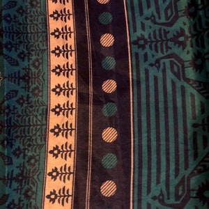 May include: A fabric with a repeating pattern of green, black, and white. The pattern includes geometric shapes, circles, and stylized trees.