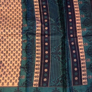 May include: A blue and white patterned fabric with a repeating design of peacocks and floral motifs. The fabric has a textured surface and a subtle sheen.