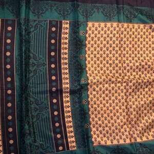 May include: A teal and black patterned fabric with a cream colored background. The fabric has a repeating geometric design.
