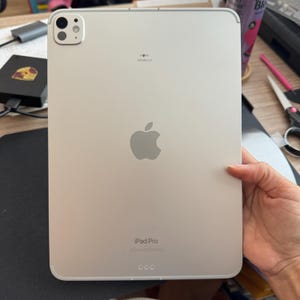 May include: A white iPad Pro with a silver Apple logo and the text "iPad Pro" on the back. The iPad has a camera bump with two lenses.