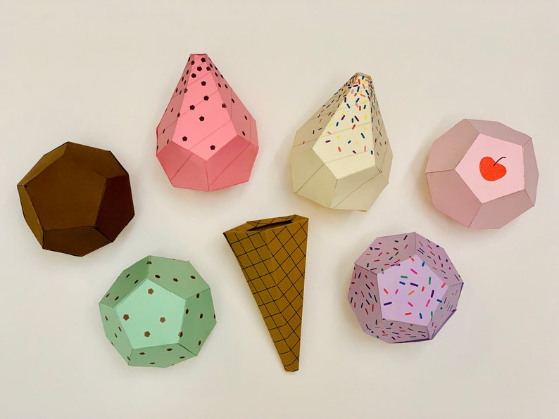 Puede incluir: Un conjunto de seis conos y bolas de helado de papel. Los conos son marrones con un patr&oacute;n de gofres. Las bolas son rosas, verdes, moradas y blancas con diferentes chispas y dise&ntilde;os.