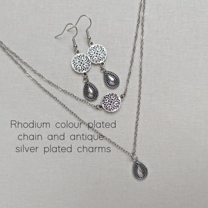 Top view of a rhodium colour plated double strand necklace with two different types of antique silver plated charms on each chain.